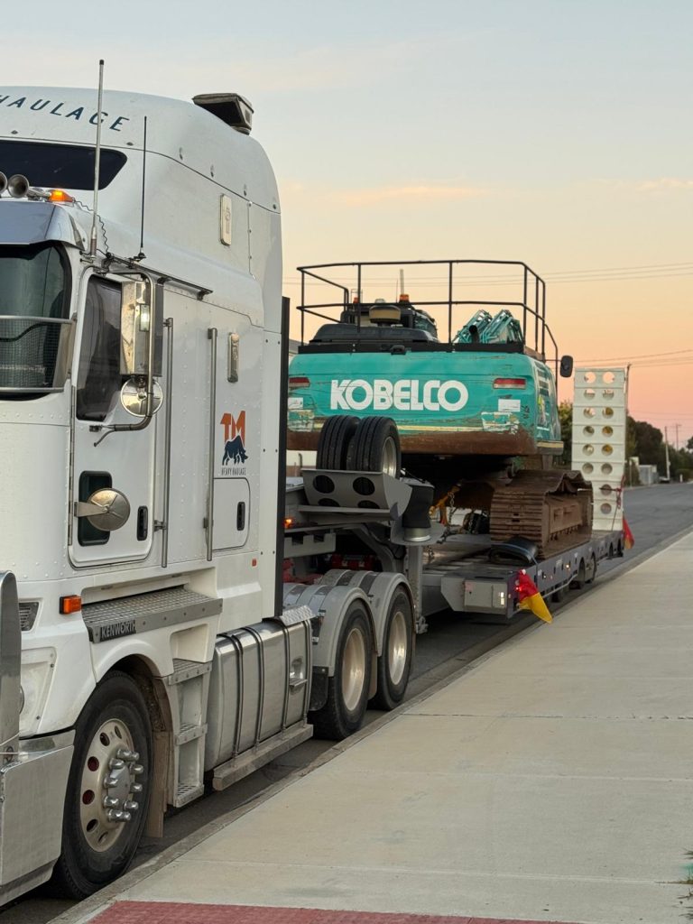 Long-Haul Interstate Freight – TM Heavy Haulage truck carrying excavator on highway